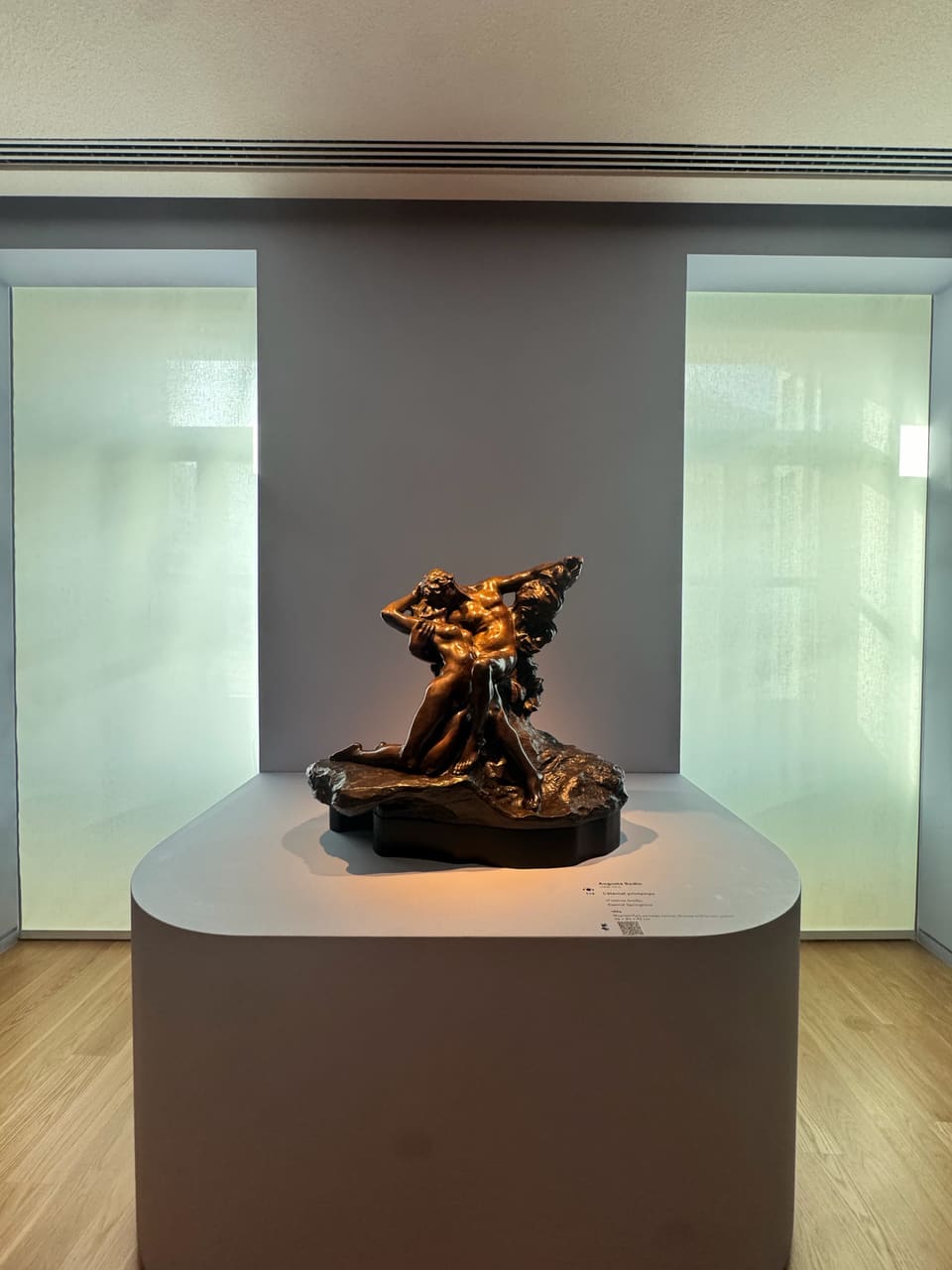 Rodin's bronze Eternal Springtime, two entwined lovers, spotlit on a pedestal in a quiet museum gallery