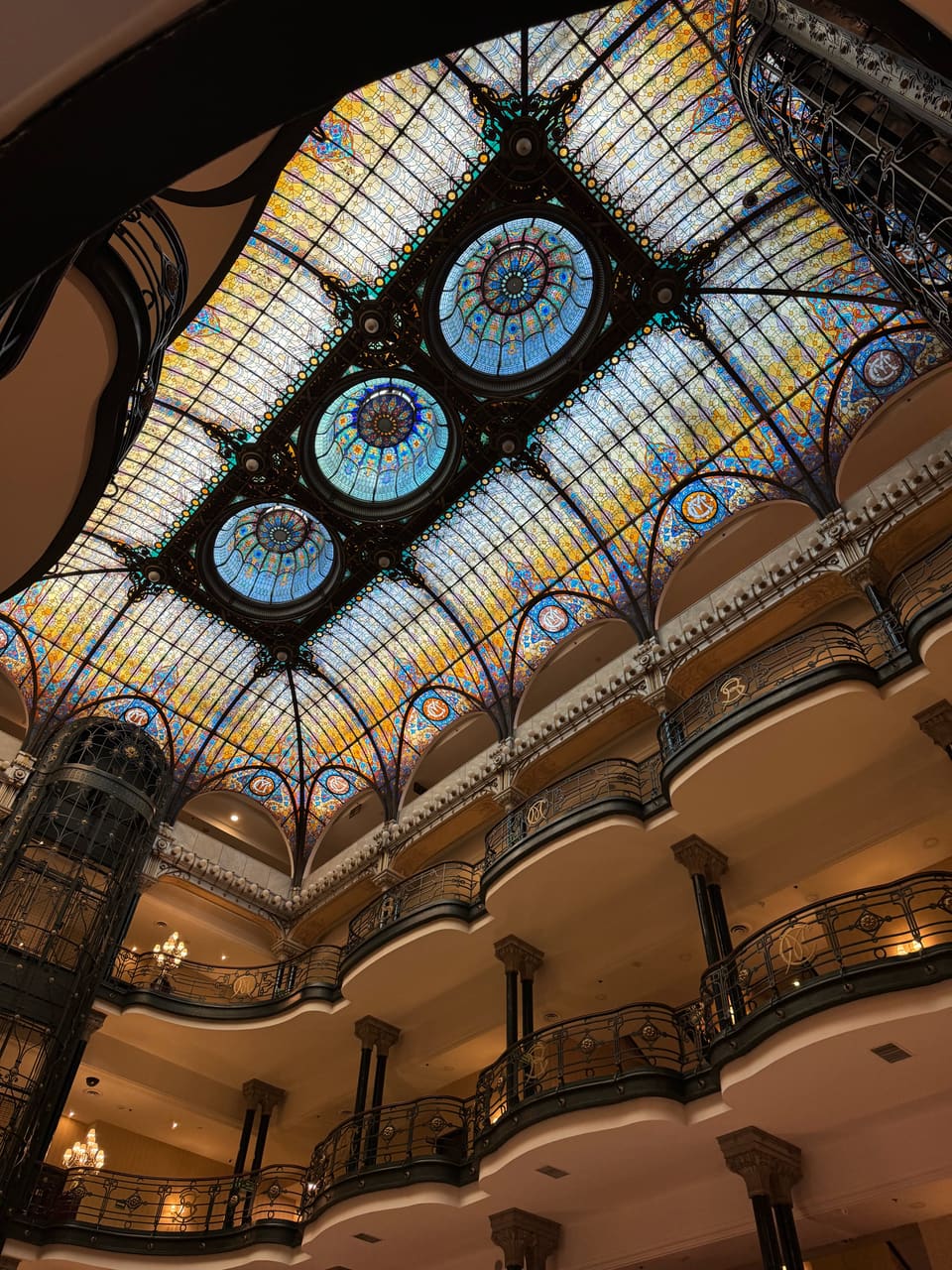 Stained-glass ceiling of the Gran Hotel Ciudad de México arching over tiers of curved iron-railed balconies